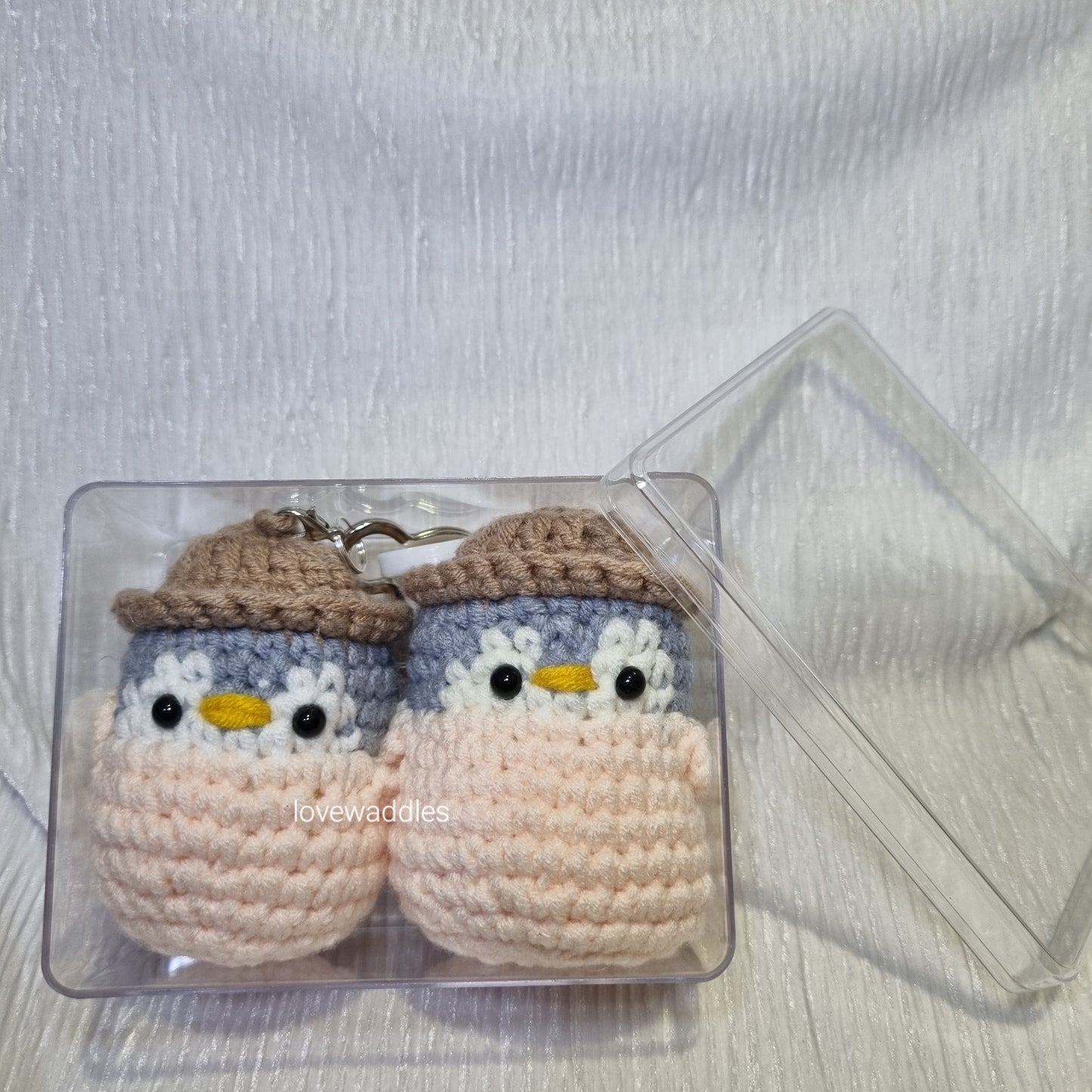 2 crochet penguins in acrylic box 