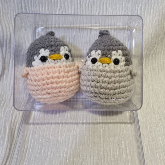 2 crochet penguins in an acrylic display case 